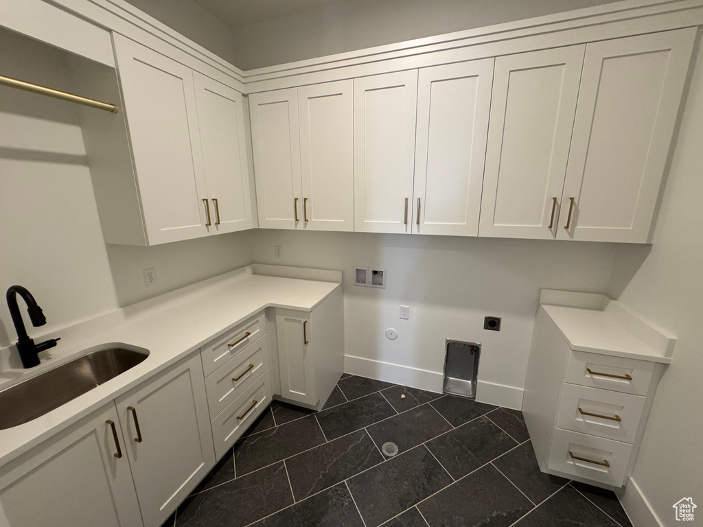 Laundry area featuring hookup for an electric dryer, cabinet space, a sink, baseboards, and hookup for a washing machine