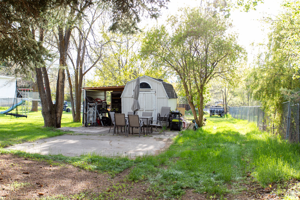 View of yard featuring fence, an outdoor structure, a patio area, and a storage unit