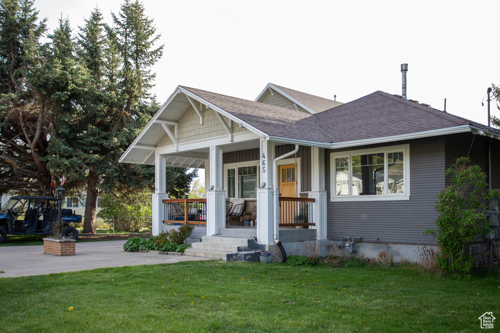 View of front facade with a shingled roof, a porch, and a front lawn
