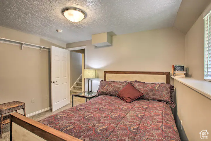 Bedroom with carpet floors, a textured ceiling, and baseboards
