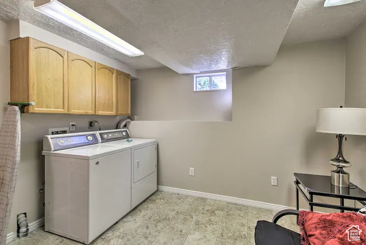 Laundry room featuring cabinet space, baseboards, a textured ceiling, and washer and dryer