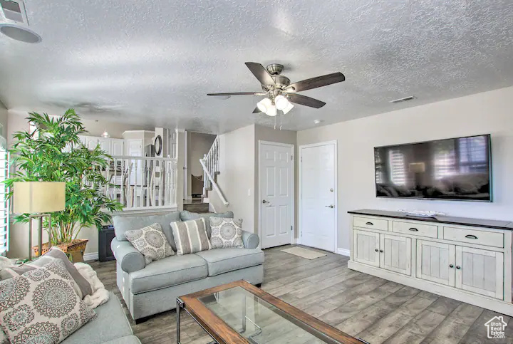 Living area featuring visible vents, wood finished floors, a textured ceiling, and stairs