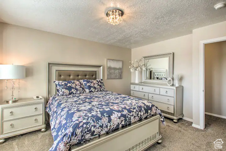 Bedroom featuring a textured ceiling, carpet flooring, and baseboards