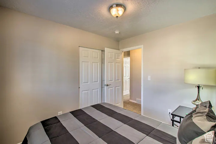 Bedroom featuring baseboards, a textured ceiling, and a closet