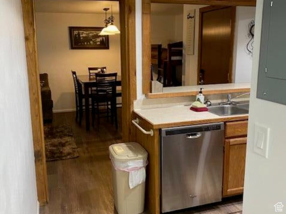 Kitchen with stainless steel dishwasher, wood finished floors, electric panel, and a sink