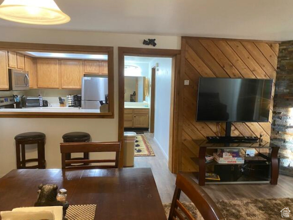 Kitchen with wood finished floors, a breakfast bar, stainless steel appliances, light countertops, and a peninsula