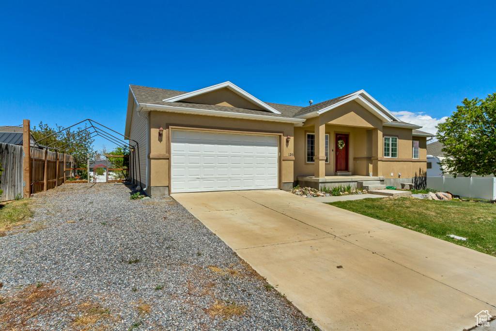 Ranch-style home with stucco siding, fence, driveway, and a garage