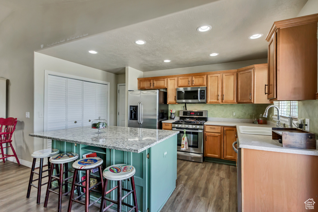 Kitchen featuring appliances with stainless steel finishes, a sink, a center island, recessed lighting, and dark wood-type flooring