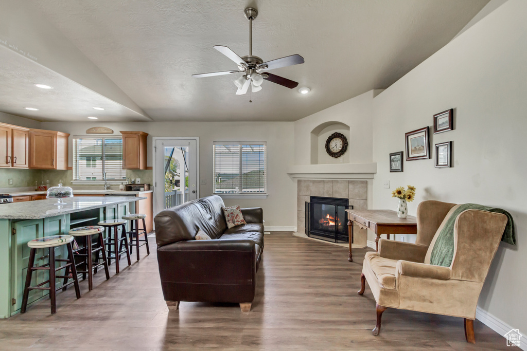 Living room featuring baseboards, a fireplace, vaulted ceiling, and light wood finished floors