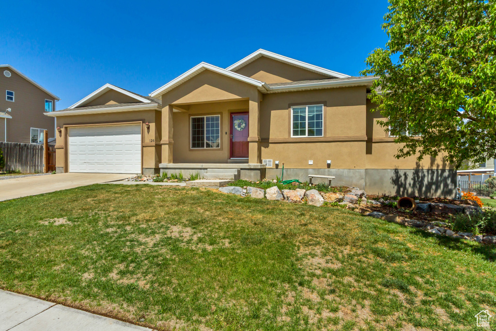 Ranch-style house featuring an attached garage, a front lawn, driveway, and stucco siding
