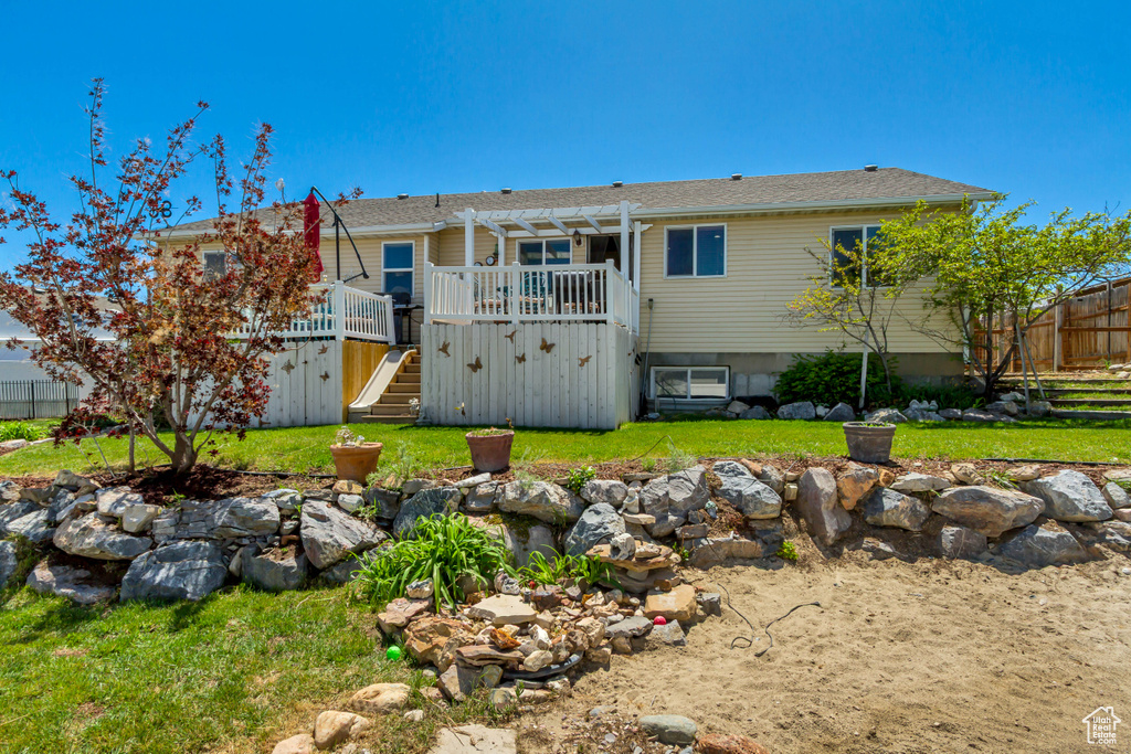 Back of property with fence, a pergola, a deck, stairs, and a yard