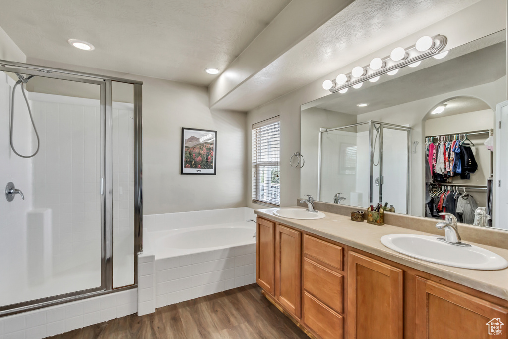 Bathroom featuring a sink, double vanity, a stall shower, and a garden tub