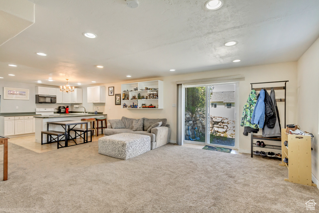 Living area featuring baseboards, light carpet, recessed lighting, and a notable chandelier