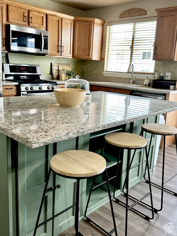 Kitchen with stainless steel appliances, light wood finished floors, a kitchen island, and backsplash