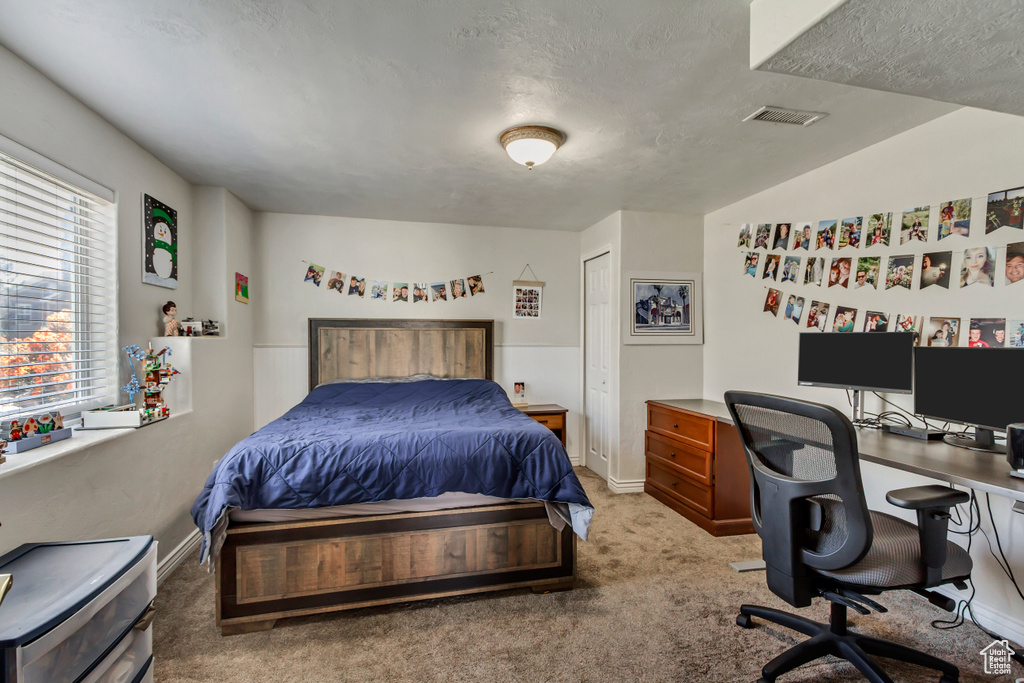 Carpeted bedroom featuring a textured ceiling, visible vents, and baseboards