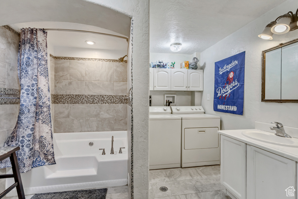 Full bathroom featuring a sink, shower / tub combo, two vanities, and washing machine and clothes dryer