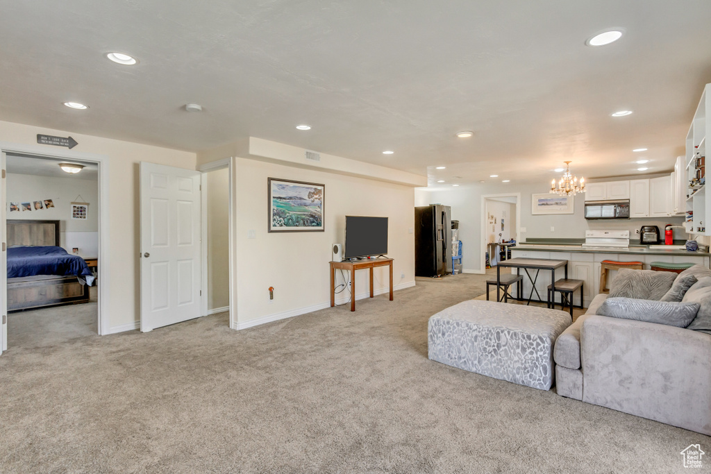Living area featuring light carpet, recessed lighting, and a notable chandelier