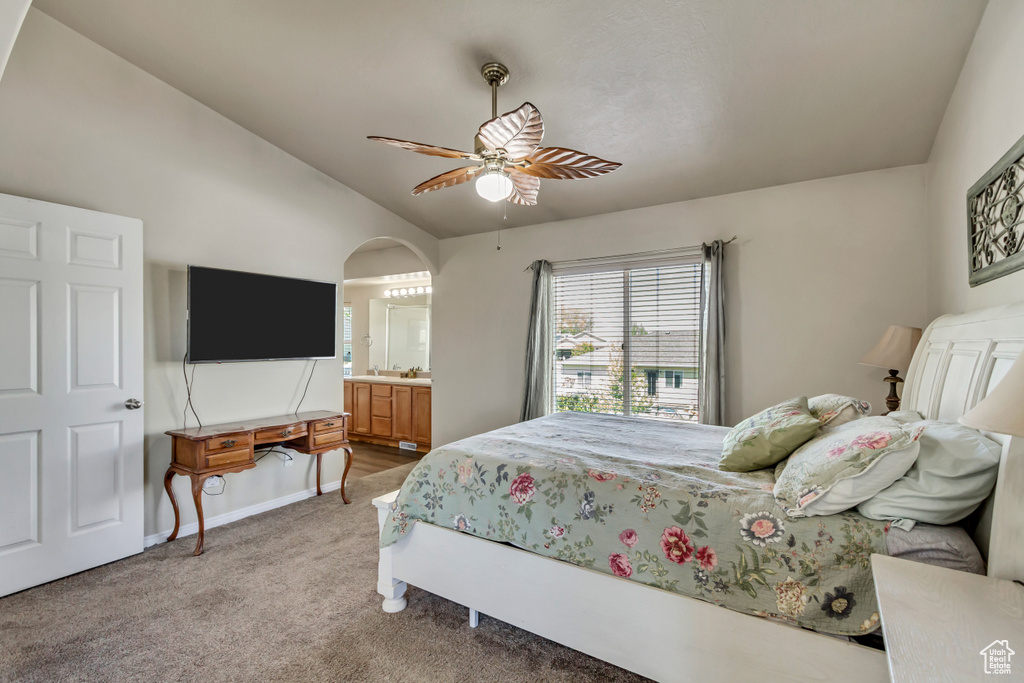Bedroom featuring lofted ceiling, ensuite bathroom, ceiling fan, light colored carpet, and arched walkways