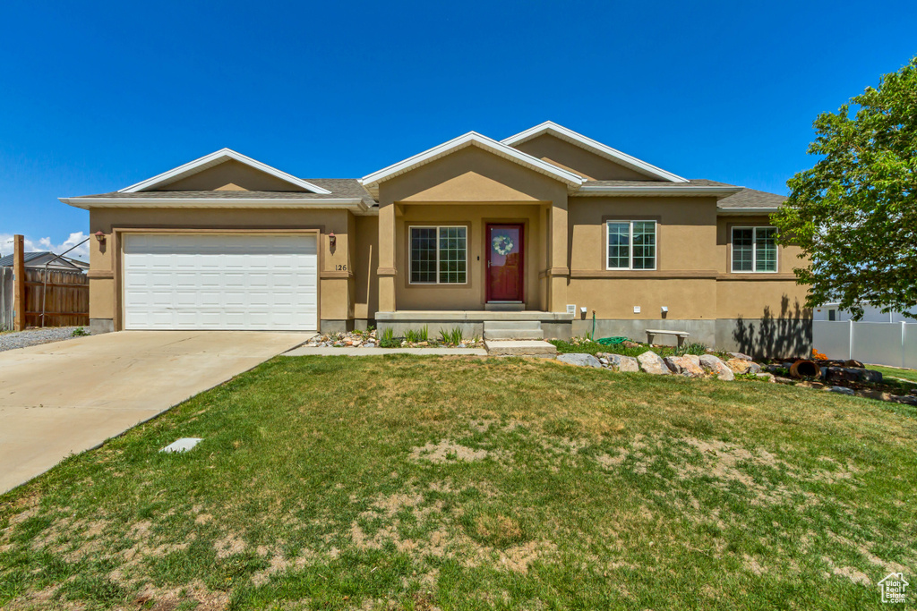 Ranch-style house with fence, an attached garage, a front lawn, stucco siding, and concrete driveway