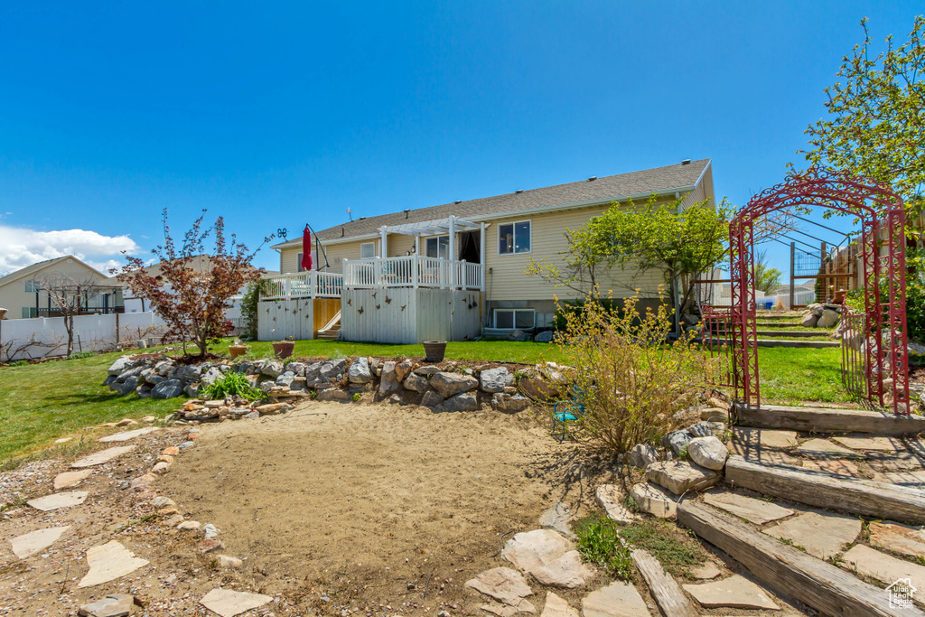 Back of house with a yard, fence, and a wooden deck