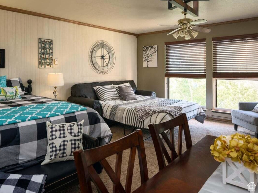 Carpeted bedroom with baseboard heating, ceiling fan, and ornamental molding