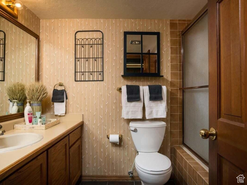 Full bathroom with toilet, vanity, and a textured ceiling