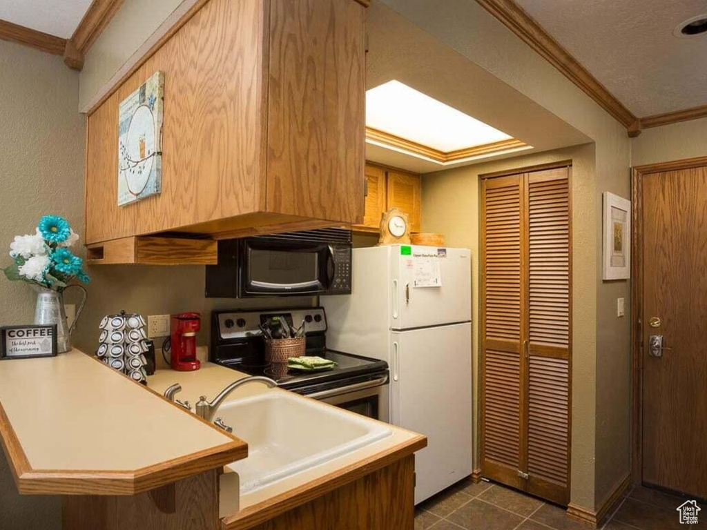 Kitchen with stainless steel range with electric cooktop, light countertops, ornamental molding, a sink, and black microwave