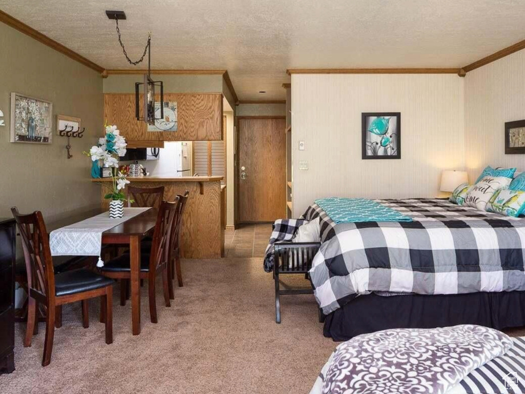 Bedroom with freestanding refrigerator, carpet, a textured ceiling, and ornamental molding