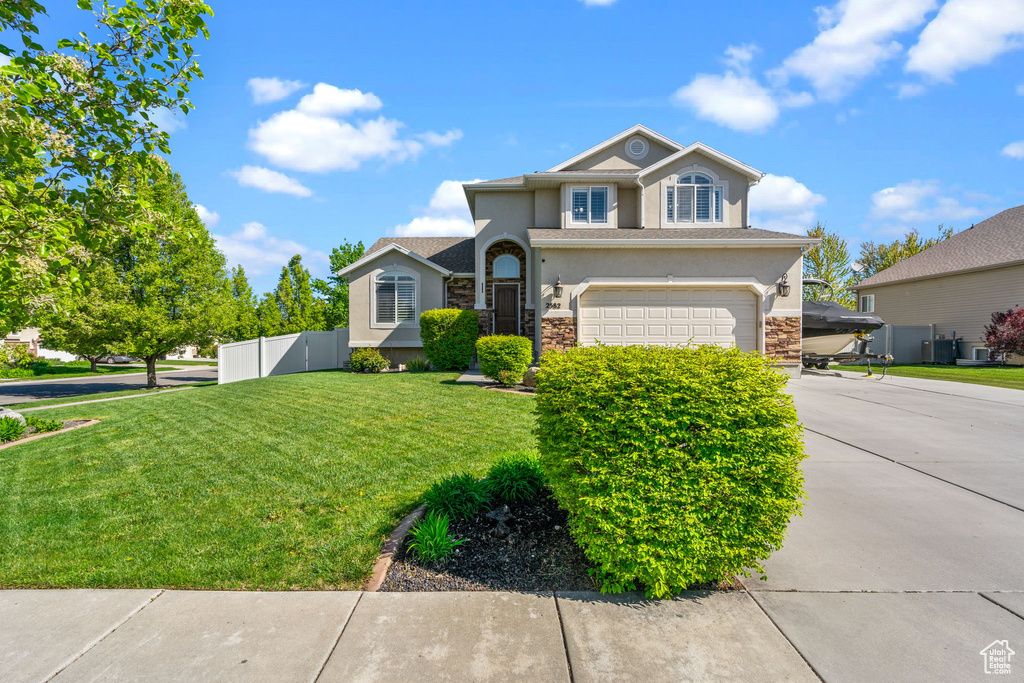 View of front facade with an attached garage, stucco siding, driveway, and stone siding