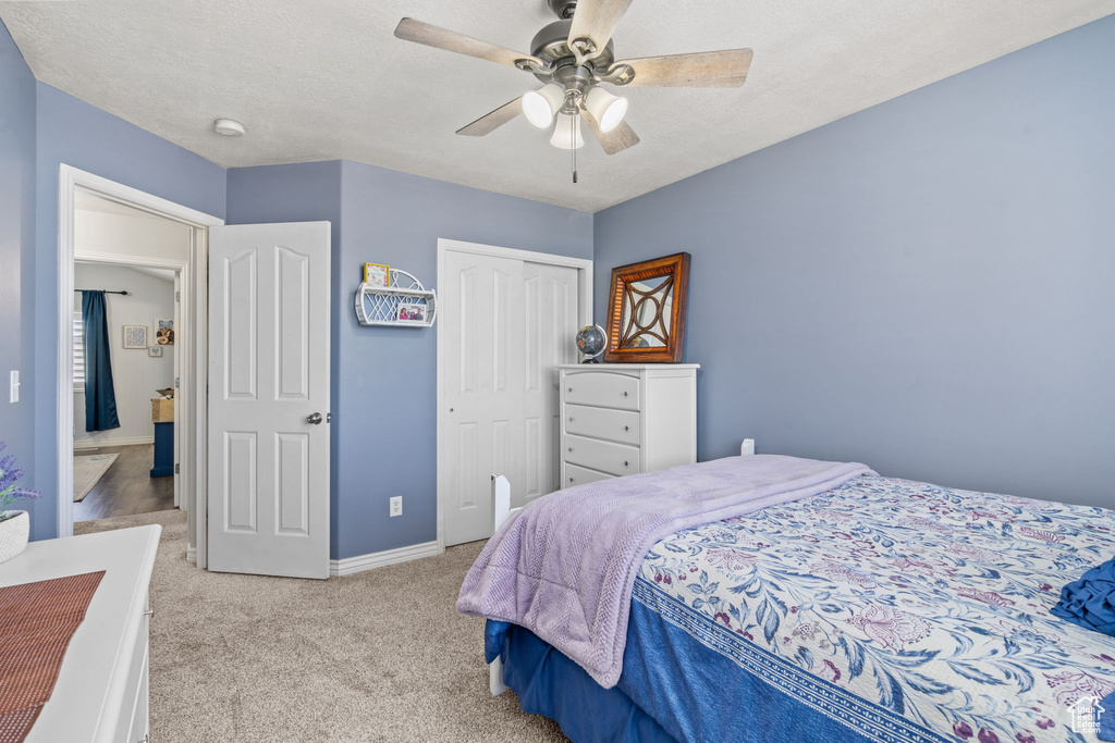 Bedroom with a ceiling fan, baseboards, light colored carpet, and a closet