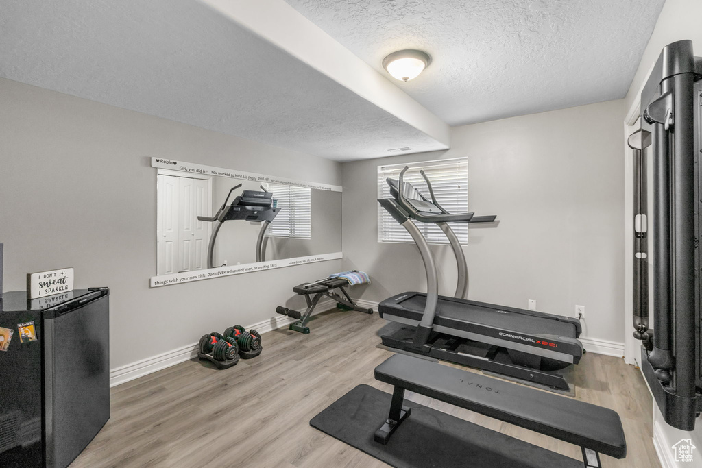 Exercise room featuring baseboards, a textured ceiling, and wood finished floors
