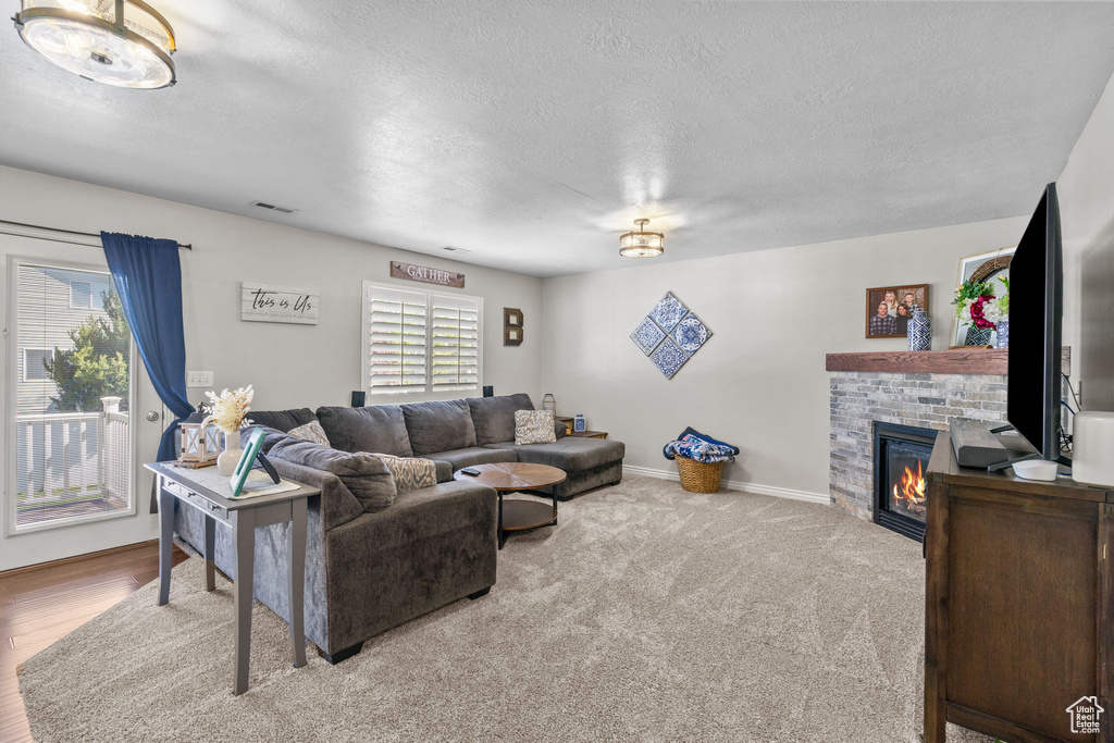 Living area with visible vents, a textured ceiling, a brick fireplace, and baseboards