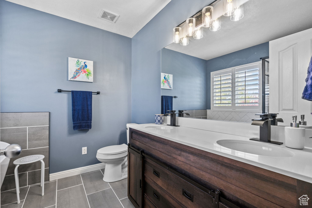 Bathroom featuring a sink, double vanity, toilet, tile patterned floors, and visible vents