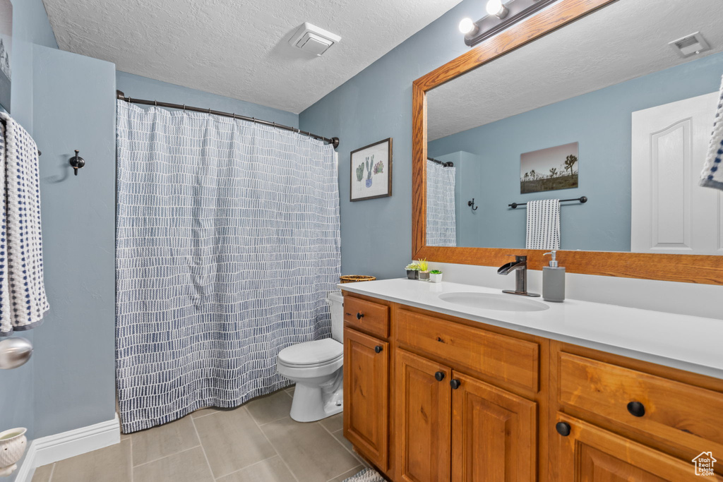 Full bathroom with toilet, a textured ceiling, visible vents, and vanity