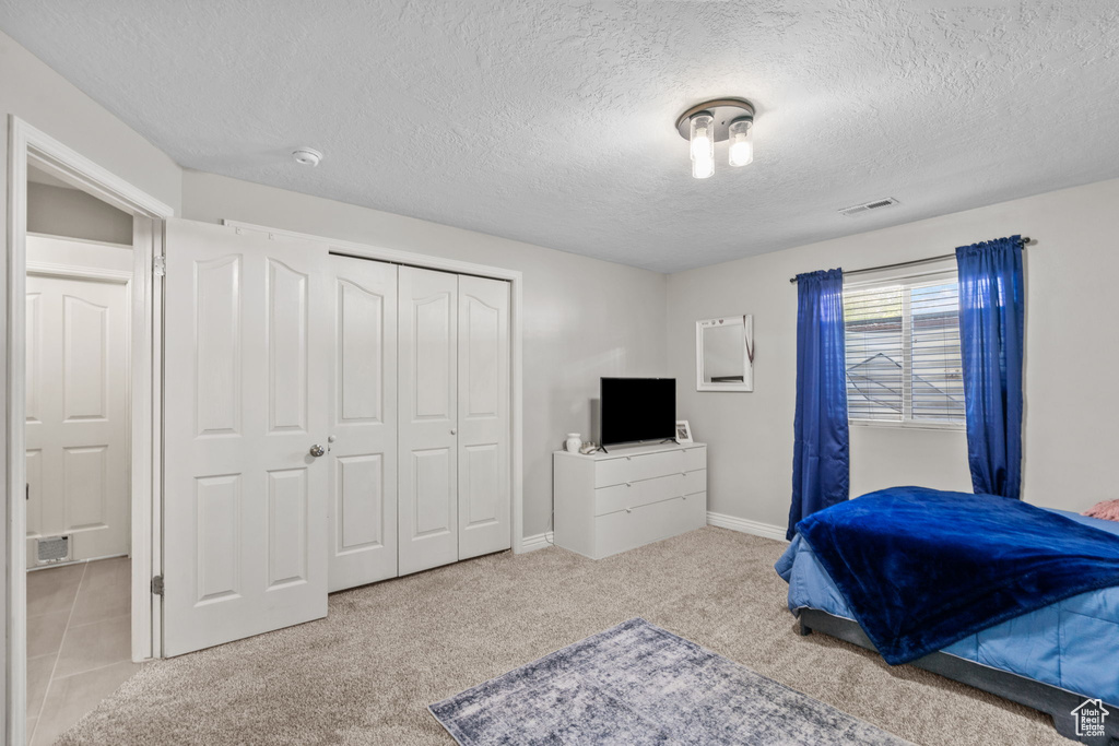 Bedroom with visible vents, carpet floors, a closet, baseboards, and a textured ceiling