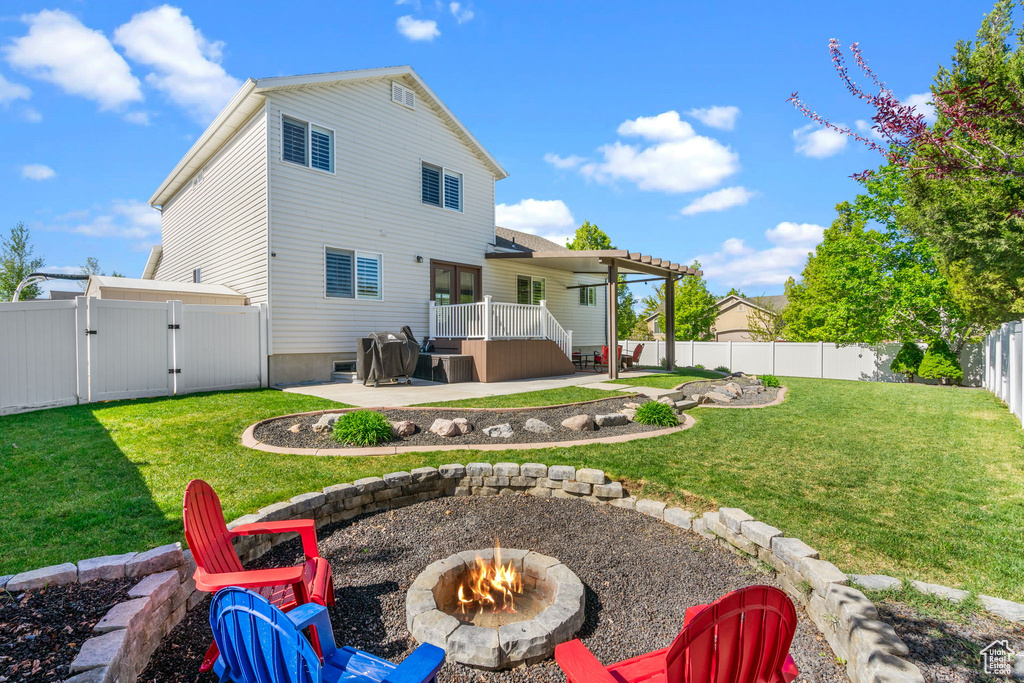 Back of house featuring a lawn, a gate, a fenced backyard, a patio, and a fire pit