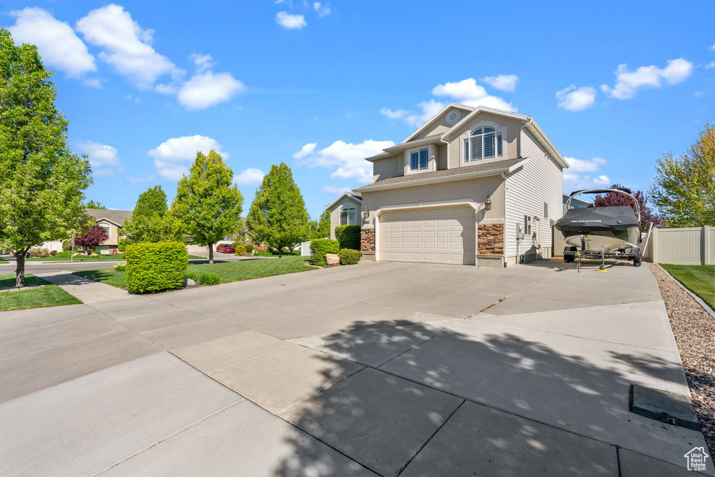 View of front of home featuring fence, a garage, driveway, and stone siding