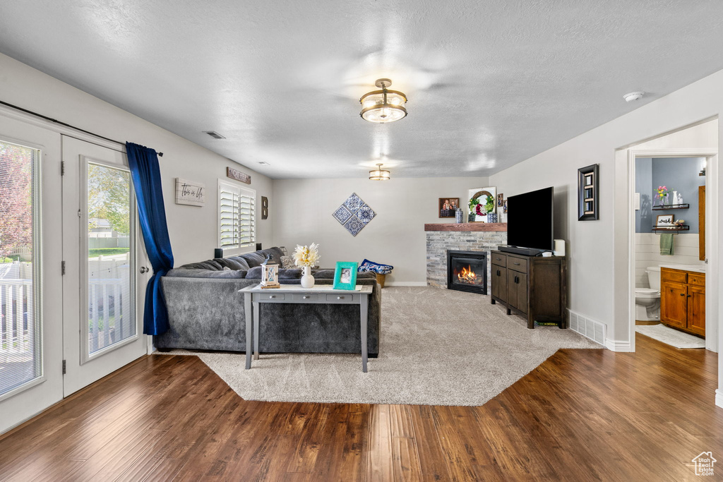 Living area featuring baseboards, visible vents, wood finished floors, and a fireplace