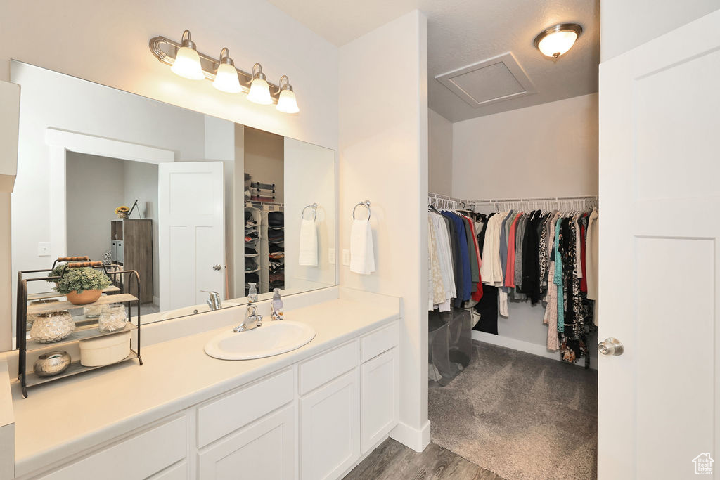 Bathroom featuring baseboards, a spacious closet, wood finished floors, and vanity