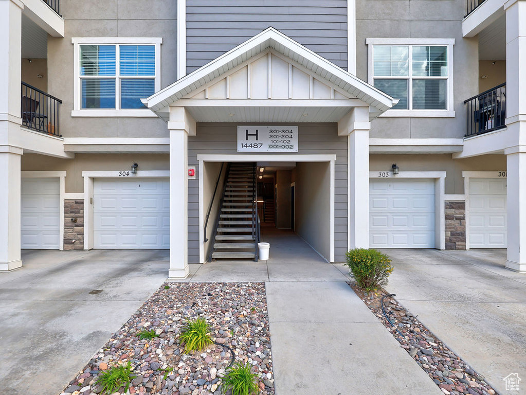 Entrance to property with an attached garage, driveway, and stone siding