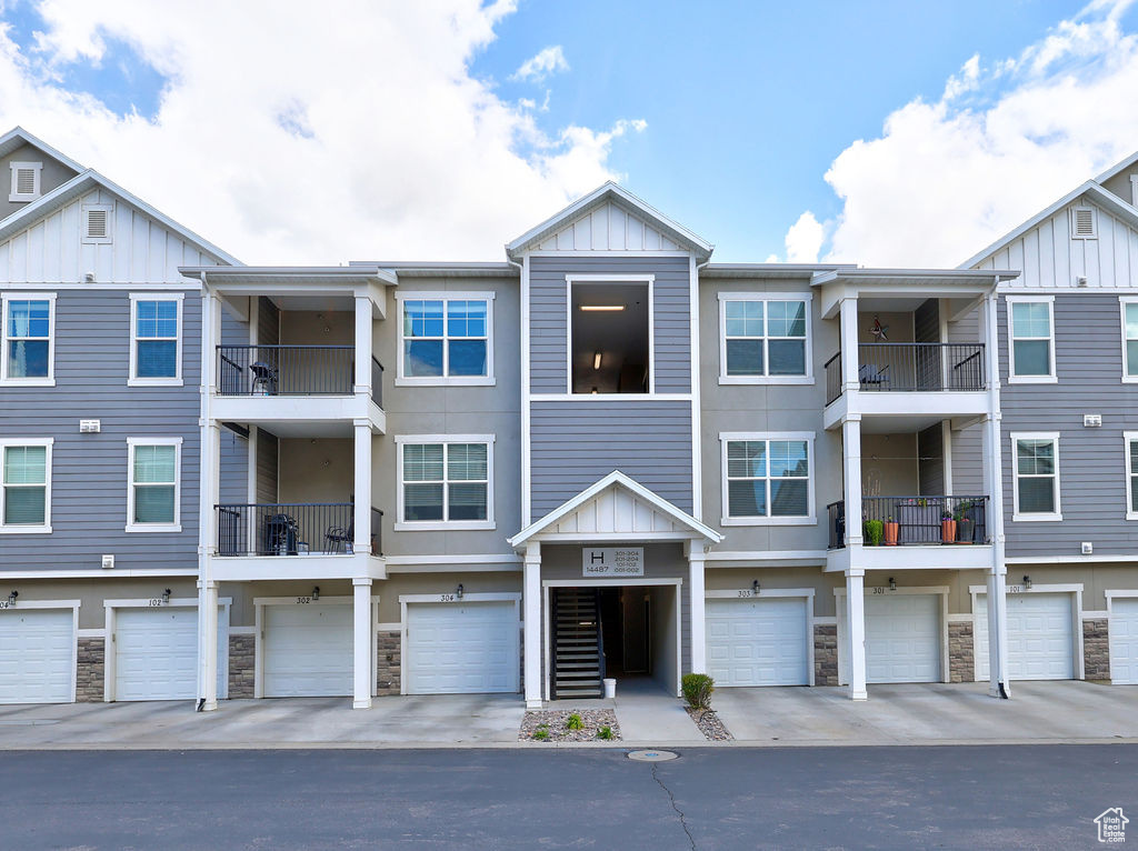 Multi unit property featuring board and batten siding, an attached garage, stone siding, and stucco siding