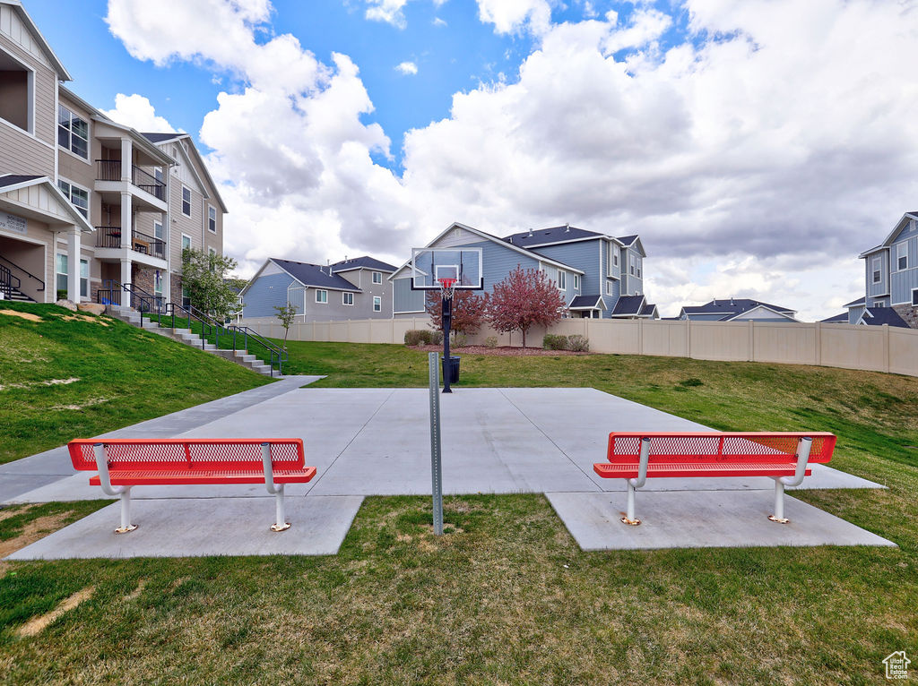 View of basketball court featuring a lawn, fence, and a residential view