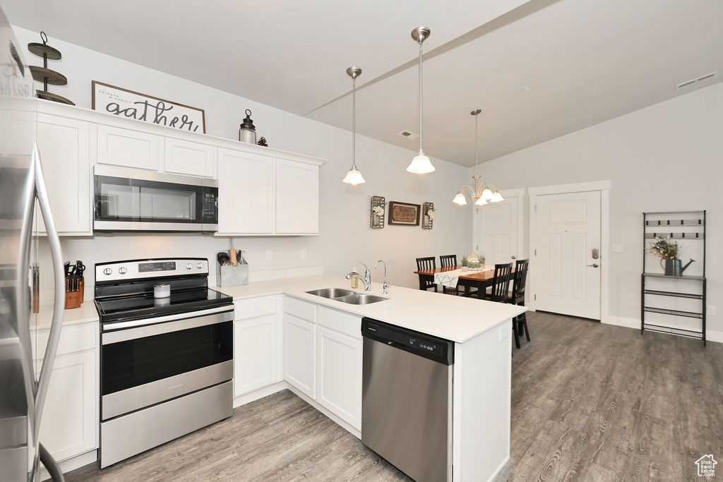 Kitchen with a sink, light countertops, a peninsula, light wood-style floors, and stainless steel appliances