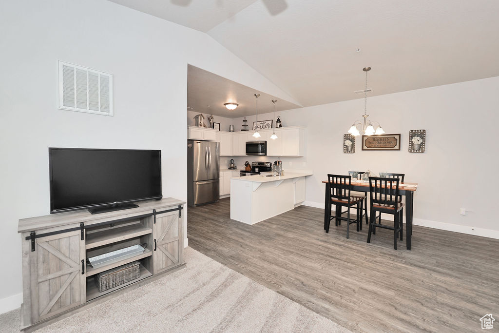 Kitchen with visible vents, a peninsula, lofted ceiling, a breakfast bar area, and stainless steel appliances