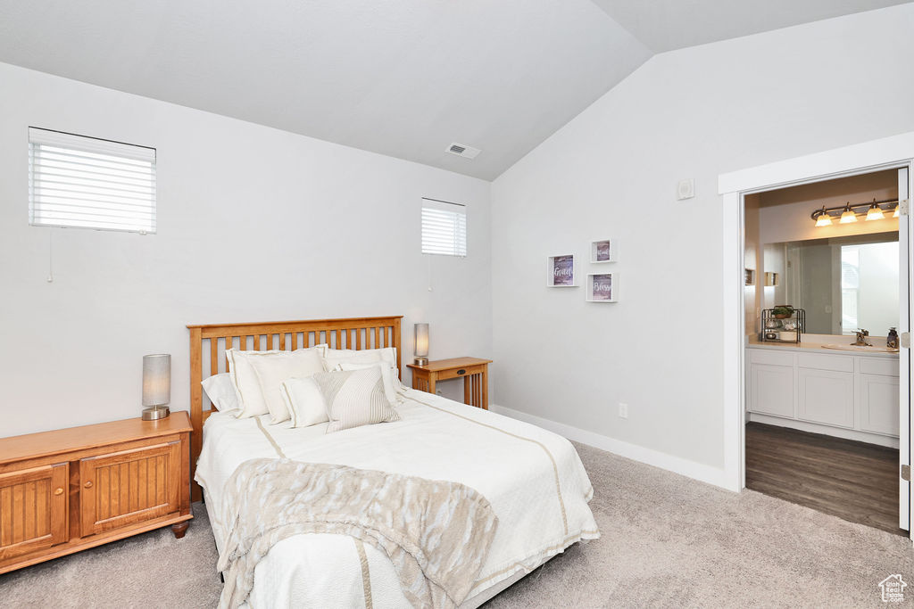 Bedroom with visible vents, carpet flooring, a sink, ensuite bath, and vaulted ceiling