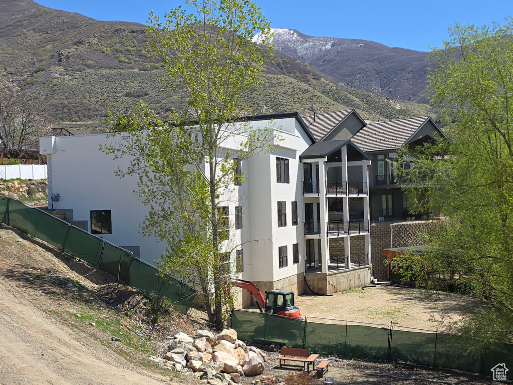 View of side of property with fence, a mountain view, and stucco siding