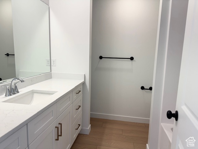 Bathroom with vanity, baseboards, and wood finished floors