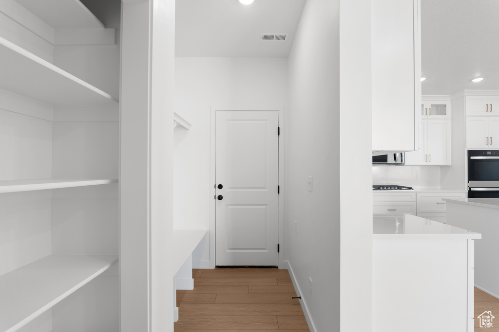 Hall featuring visible vents, light wood-style flooring, baseboards, and recessed lighting