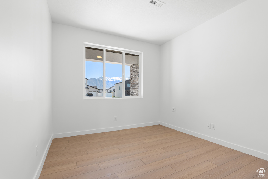 Spare room with baseboards, light wood finished floors, and visible vents