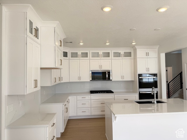 Kitchen with glass insert cabinets, recessed lighting, white cabinets, a sink, and black appliances